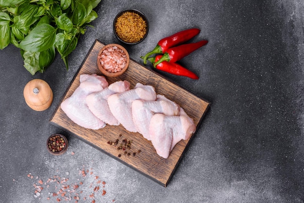 Raw chicken wings with ingredients for cooking on a wooden cutting board