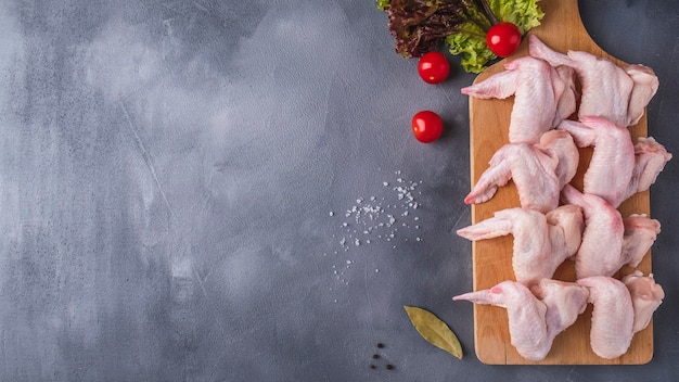 Raw chicken wings on a wooden cutting board  ingredients for cooking. Top view.