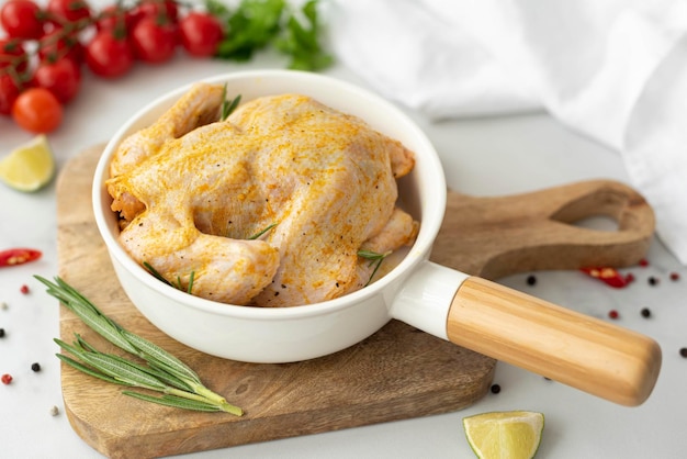 Raw chicken with sauce and spices in a round baking sheet