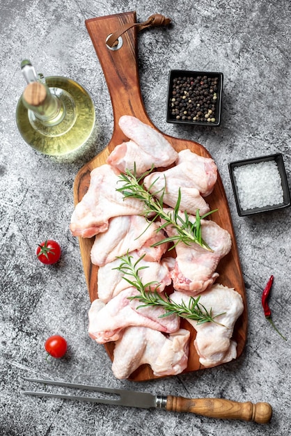 Raw chicken on a wooden board with ingredients for cooking.