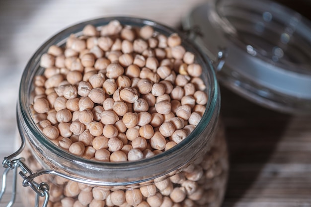 Raw chickpeas in a glass jar on an old wooden Board. Healthy vegan product