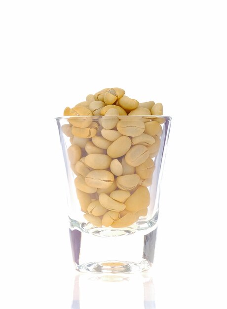 Raw coffee beans in glass on white background.