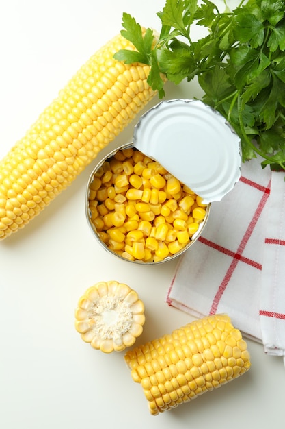 Raw corn and canned corn on white table