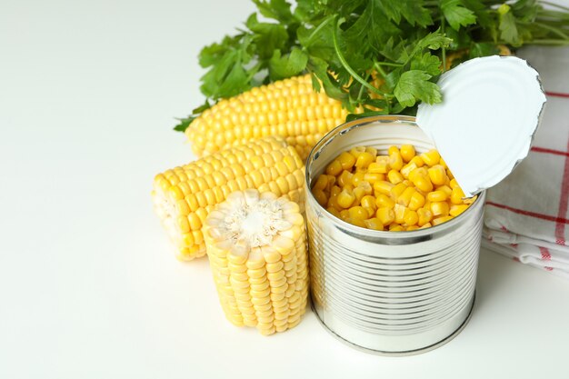 Raw corn and canned corn on white table