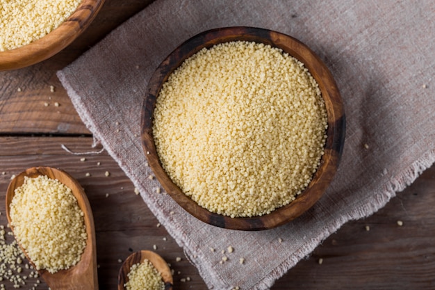 Raw Couscous in a wooden bowl on the table