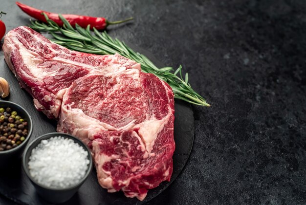 raw cowboy beef steak on stone background