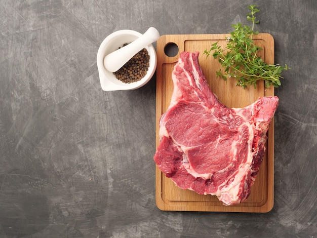 Raw cowboy steak with seasonings on stone background rib eye on bone