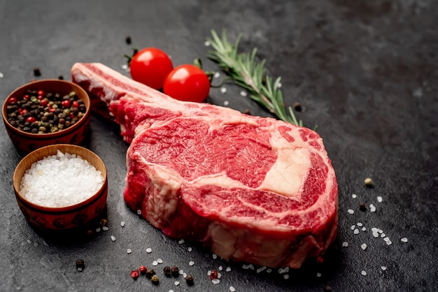 Raw cowboy steak with spices on stone background