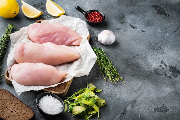 Raw crumbet chicken fillet with ingredients on grey table