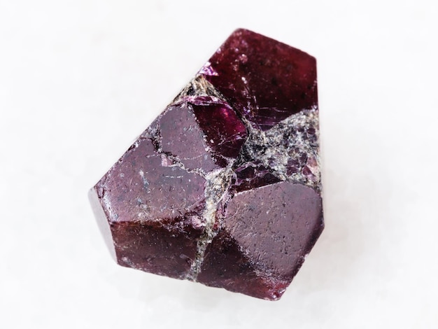 Raw crystal of red garnet gemstone on white