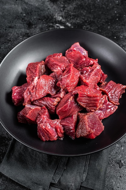 Raw Diced game meat of wild venison dear Black background Top view