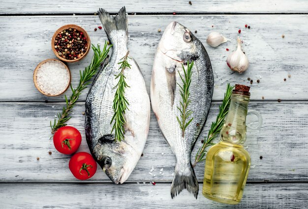 Raw dorado fish with spices and ingredients tomato, razmorin, sunflower oil, lemon on a wood background