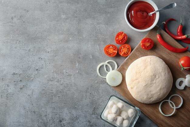 Raw dough with ingredients for pizza on kitchen table