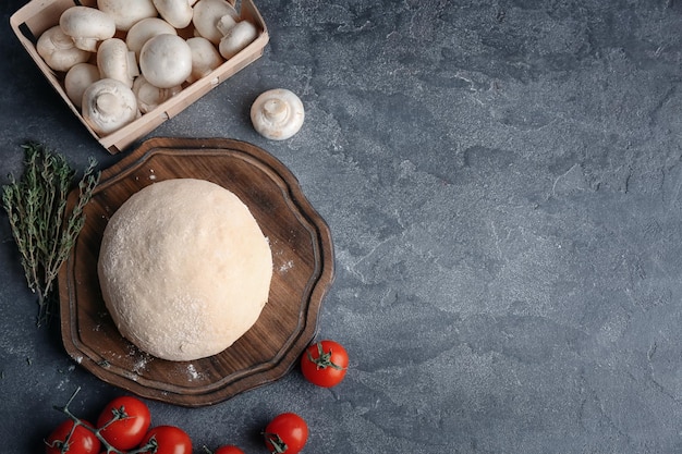 Raw dough with ingredients for pizza on kitchen table