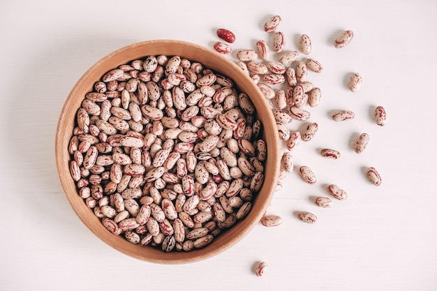 Raw dry beans in a wooden bowl on a white background. Top view. Copy, empty space for text