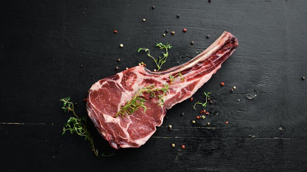 Raw dry steak cowboy on black background Tomahawk steak BBQ Top view Free space for text