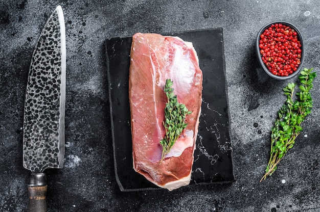 Raw duck breast fillet on a marble board. Black background. Top view.