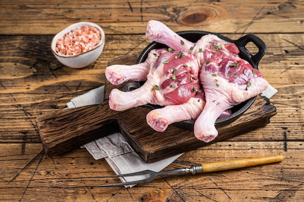 Raw Duck drumsticks in a pan with herbs. wooden background. Top view.