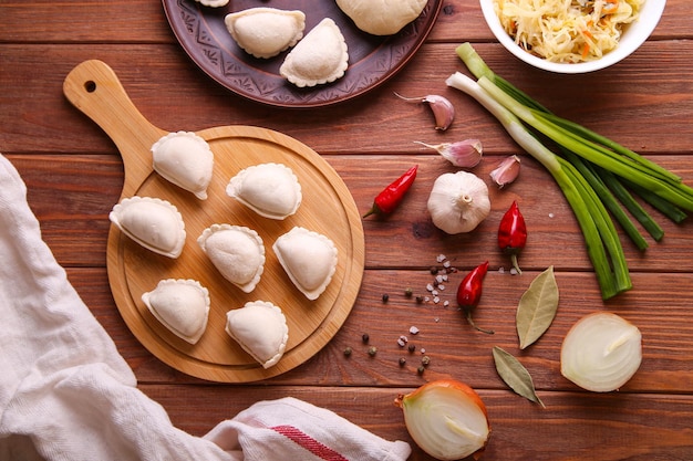 Raw dumplings with cabbage on a wooden background.