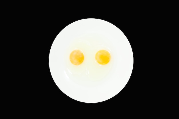 Photo raw egg yolks in a white bowl isolated on a black background to prepare for a high protein diet has helped in the growth of a person's body