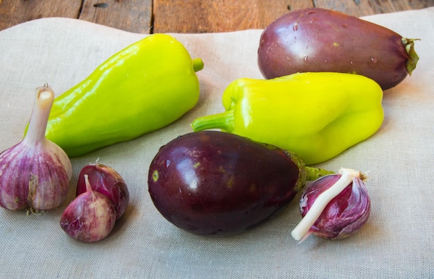 Raw eggplant garlic bell peppers healthy eating and diet concept on the old wooden background