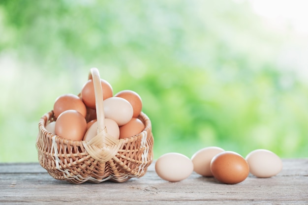 Raw eggs in basket on wooden table outdoor