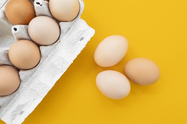 Raw eggs on yellow background