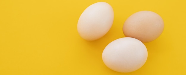 Raw eggs on yellow background