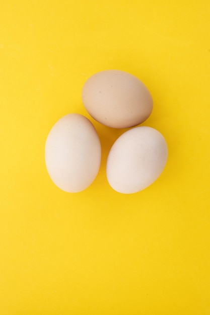 Raw eggs on yellow background