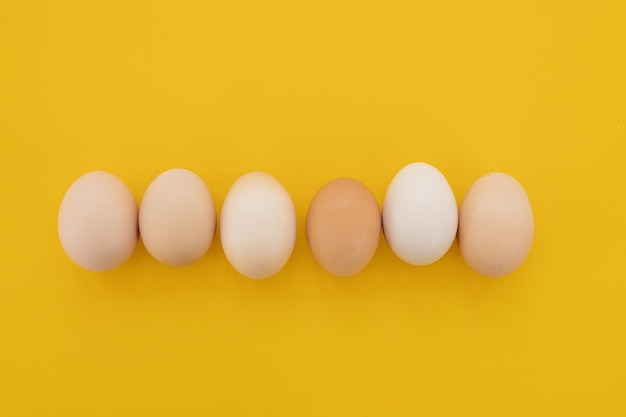 Raw eggs on yellow background