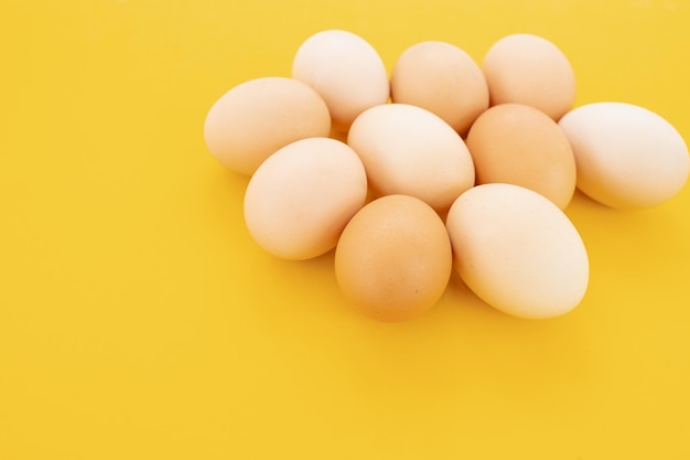 Raw eggs on yellow background