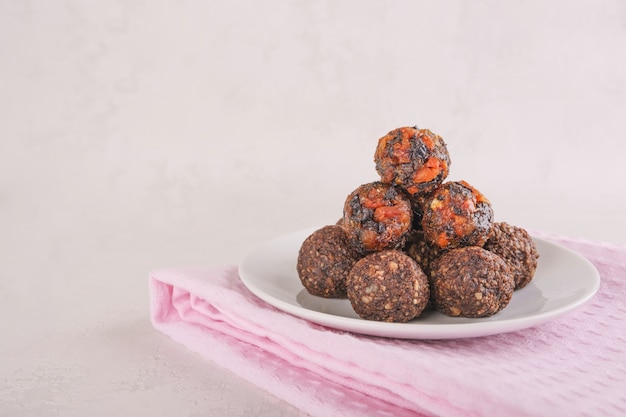 Raw energy balls with dried apricots, nuts and dates on a gray table