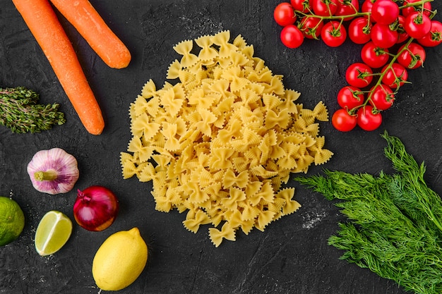 Raw farfalle with ingredients on a table