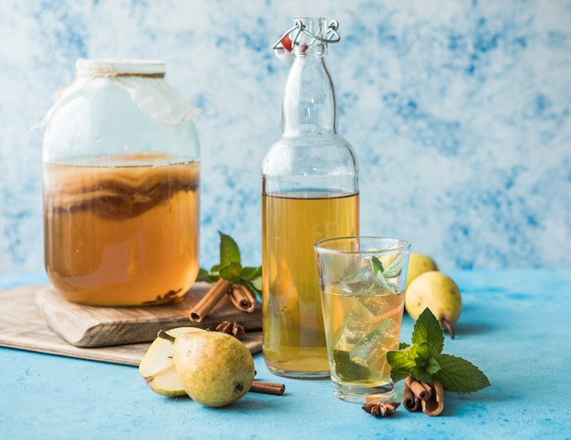 Raw fermented homemade alcoholic or non alcogolic kombucha superfood. Ice tea with healthy natural probiotic in glass with mint on  blue background