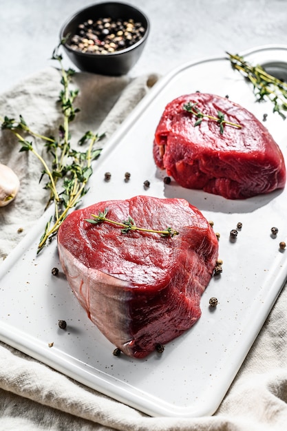 Raw filet Mignon steak on a white chopping Board. 