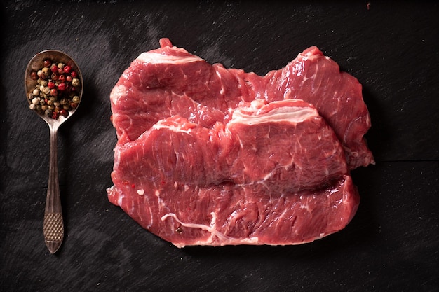 Raw fillet of beef steak with  spices on black stone close up