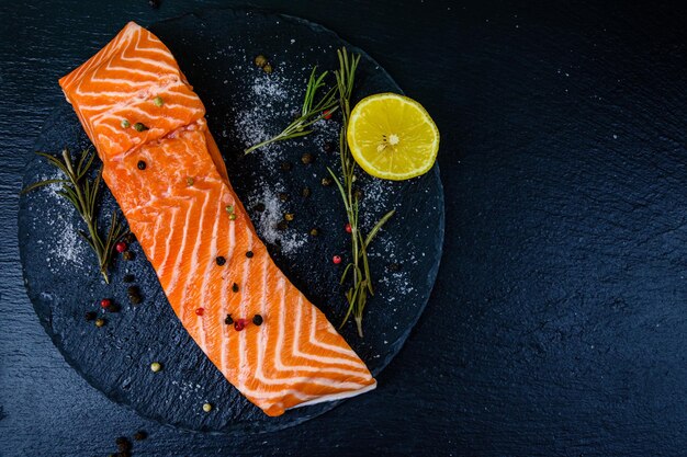 Raw fillet of salmon fish and spices on a slate board. Top view