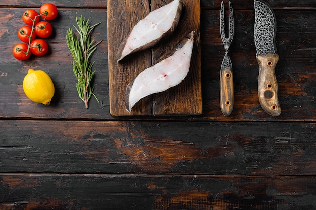 Raw fish cut set, with ingredients and rosemary herbs, on old dark  wooden table background, top view flat lay, with copy space for text