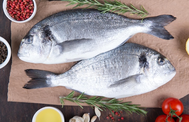 Raw fish dorado cooking and ingredients Dorado lemon tomato herbs and spices Top view on wood table