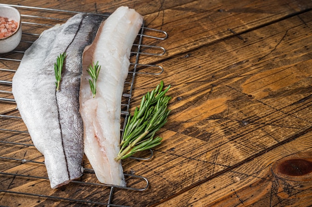 Raw fish fillets on grill with rosemary and herbs Wooden background Top view Copy space