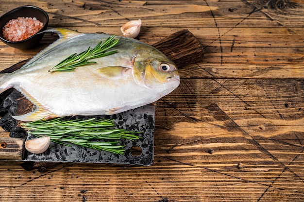 Raw fish Sunfish or pompano on a  wooden board. wooden background. Top view. Copy space.