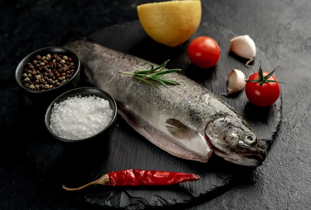 raw fish trout with spices ready for cooking on a stone background