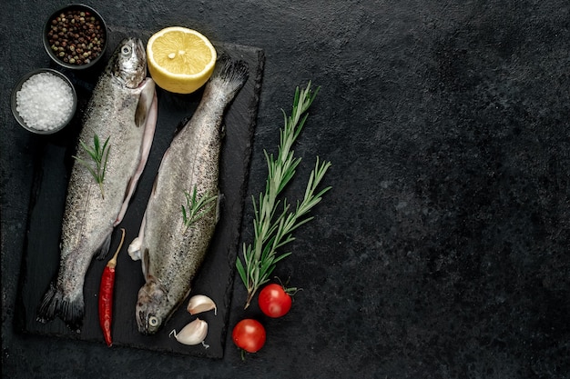 Raw fish trout with spices ready for cooking on a stone background