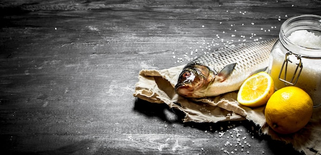 Raw fish with salt and lemon. On a black wooden background.