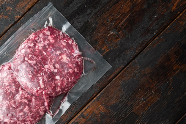 Raw fresh beef burgers minced meat in plastic tray on old dark wooden table background top view flat lay with copy space for text