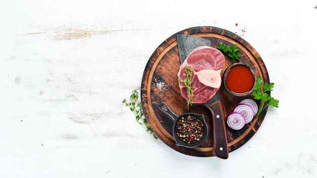 Photo raw fresh cross cut veal shank with spices and herbs on a white background cheese bif steak ossbo top view free space for your text