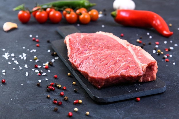 Raw fresh marbled meat and seasonings on dark background