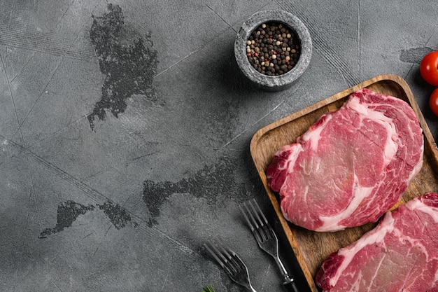 Raw fresh marbled meat Steak Ribeye set, on gray stone table background, top view flat lay, with copy space for text