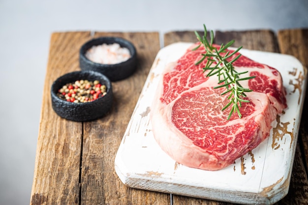 Raw fresh meat Ribeye Steak and seasonings on wooden background rustic style