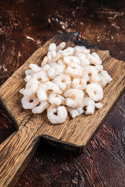 Raw fresh Peeled Shrimps Prawns set on wooden board Dark background top view